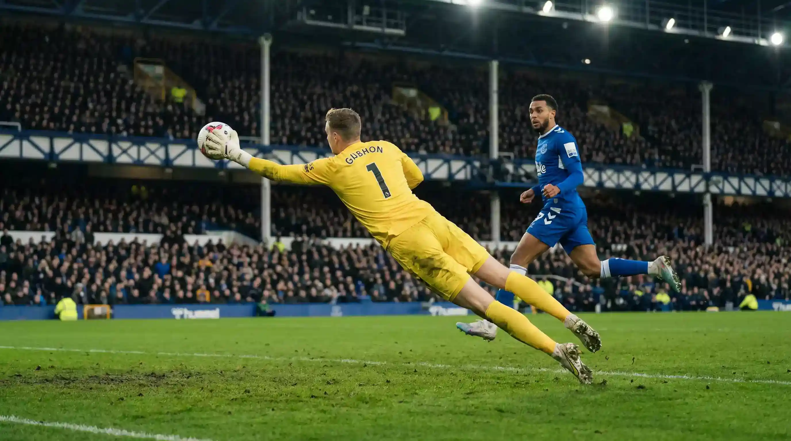 Målmand dykker efter bolden mens angriber løber mod målet på en VM-bane