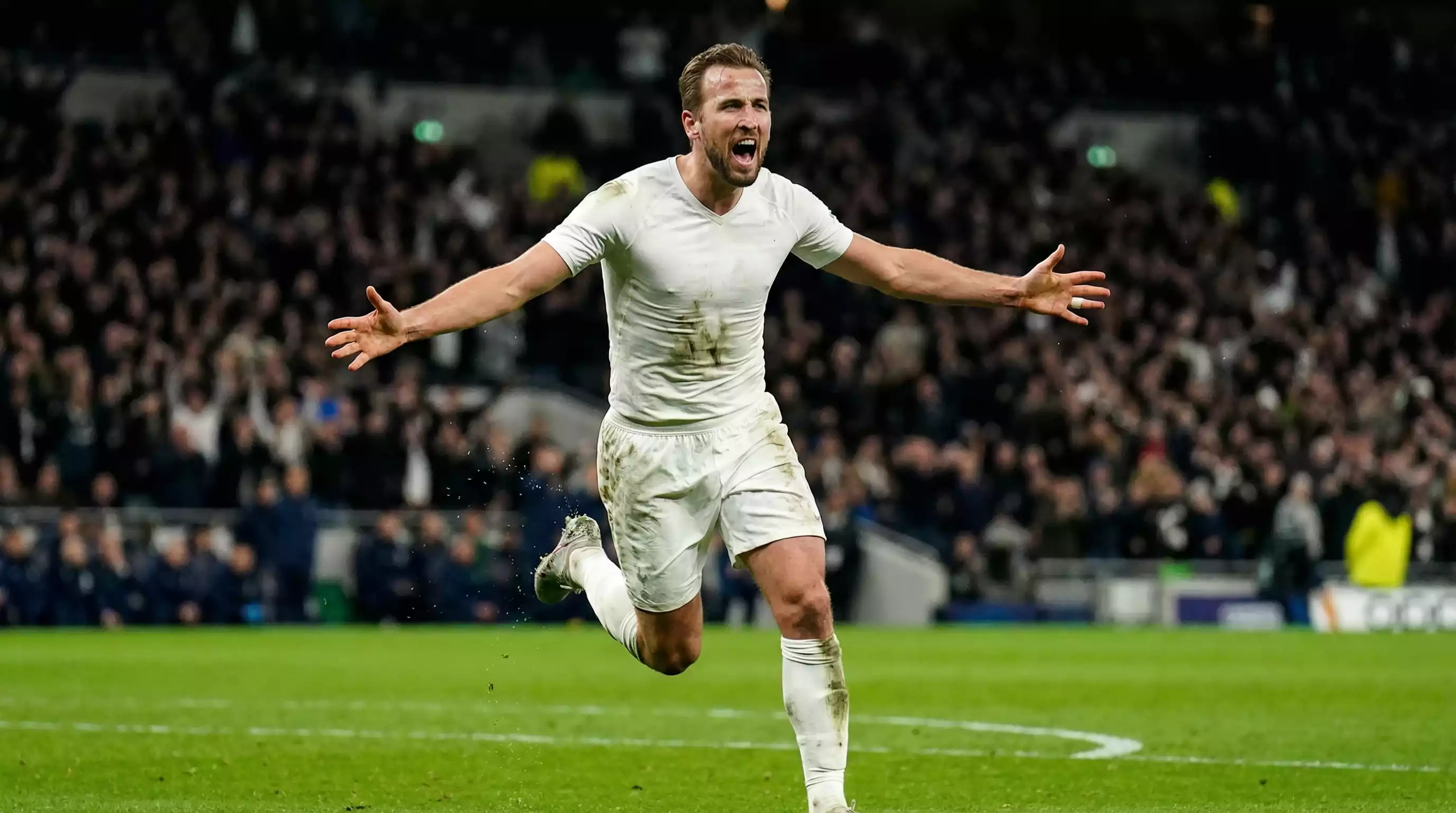 Angriber i hvidt landsholdssæt jubler efter scoret mål på græsbanen