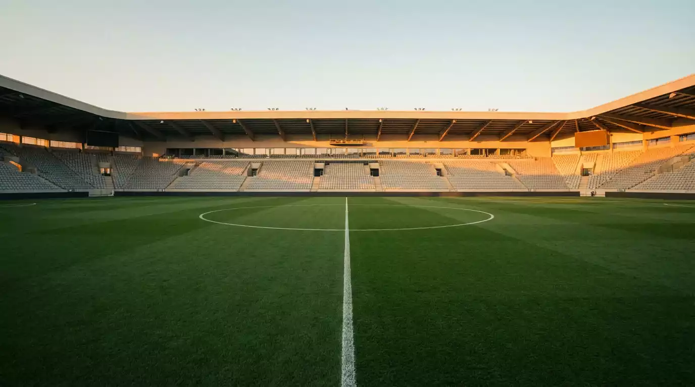 Tom fodboldstadion i aftensol med midterlinjen i forgrunden