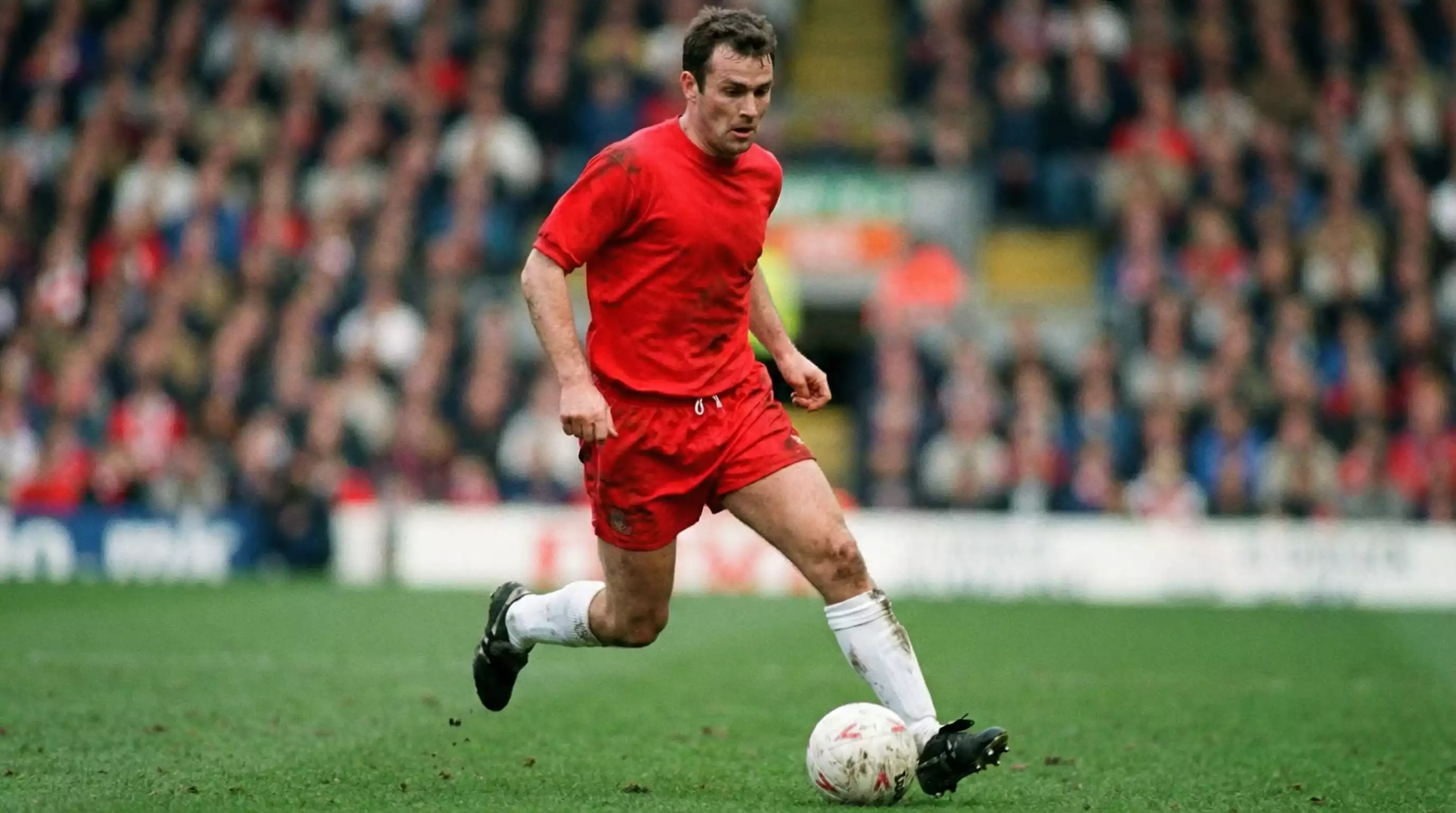 Norsk fodboldspiller i rødt landsholdssæt med bolden på kunstgræsbane