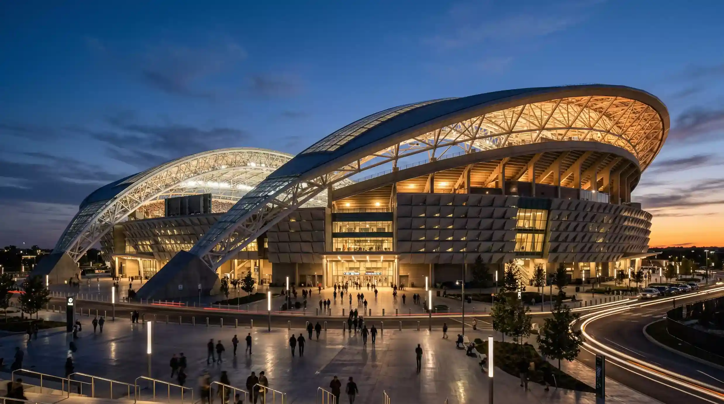 Moderne fodboldstadion set udefra med bueformet tag og aftenbelysning