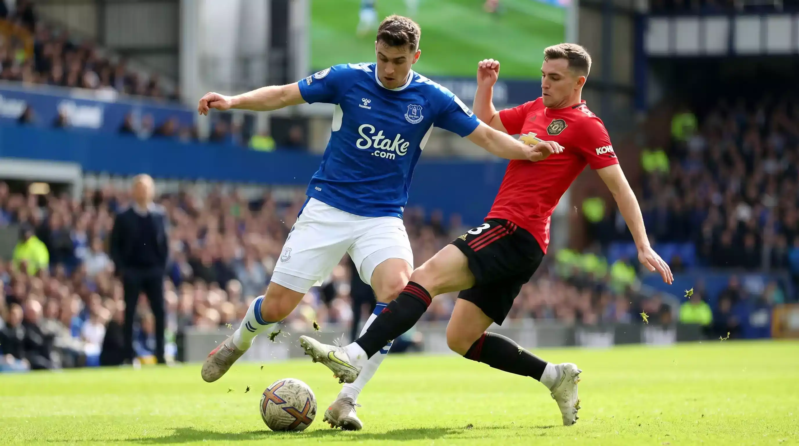 Fodboldspillere under en kamp med spilleren der driver bolden fremad på grønt græs